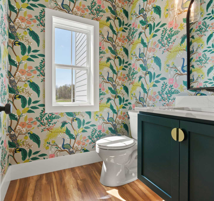 Bathroom with green vanity cabinets and nature-themed wallpaper, showcasing stylish cabinetry for modern home renovations.