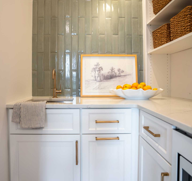 Compact kitchen nook with pale green cabinets and brass handles, offering a refined and functional cabinetry solution.