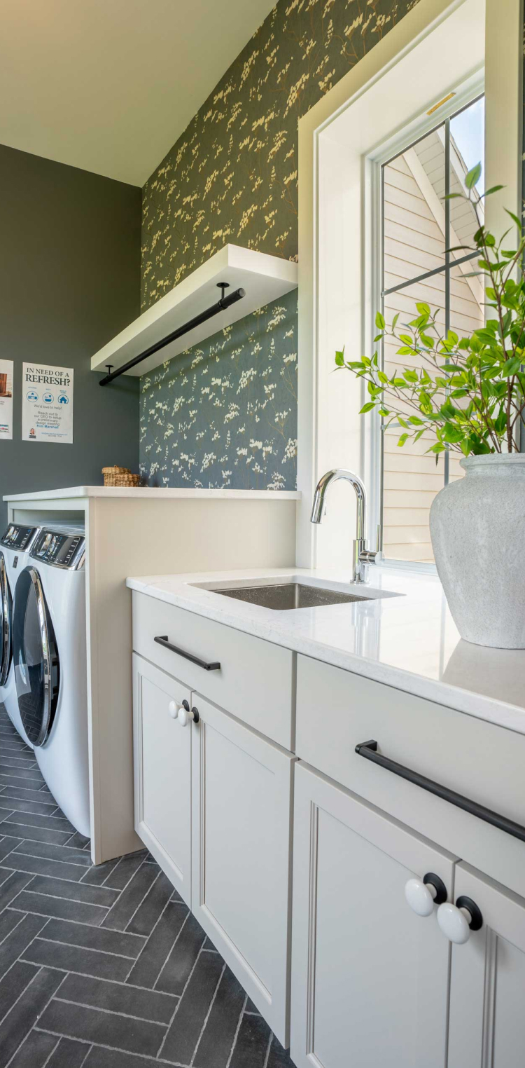 Bright laundry room with white cabinets and black hardware, providing elegant, practical storage with StarMark Cabinetry.